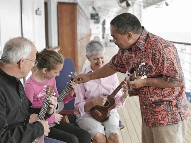 A family takes a ukulele lesson together on board their Hawaiian cruise ship.