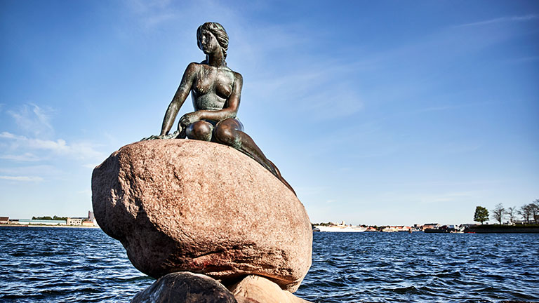 A statue of a woman sitting on a rock in Copenhagen