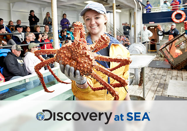 Discovery at Sea logo; Woman holding spider crab